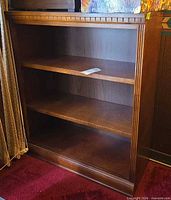Front view showing entire wooden bookcase with two shelves and decorative trim