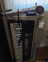 Keyboard box with digital horn and power cord resting on top