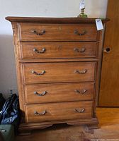 Front view of five-drawer wooden chest showing handles and overall condition