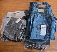 Stack of folded jeans, some still in plastic with tags visible