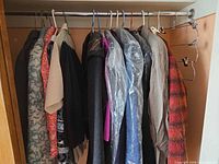 Closet view showing multiple jackets, coats, slacks and blouses on hangers