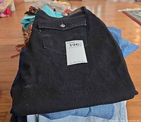Stack of jeans, top black pair with retail tag