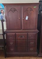 Full view of brown wood armoire with doors and drawers