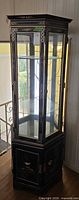 Full view of black lacquer Asian motif display cabinet with glass sides and bottom storage