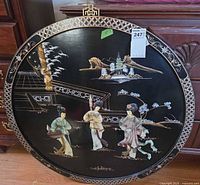 Full view of the round black lacquer wall plaque showing entire inlaid scene and border