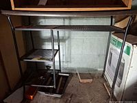 Full view of metal desk showing top, frame, and mesh shelves