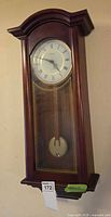 Full view of wood case wall clock hanging on wall