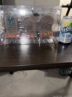 Three tombstones in packaging alongside pop can for scale