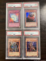 Four PSA-graded Yu-Gi-Oh cards front view in slabs