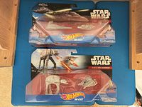 Front view of both packaged Star Wars Hot Wheels vehicles: Imperial Star Destroyer (top) and AT-AT Walker (bottom)
