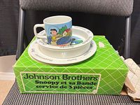 Box with Johnson Brothers Peanuts dish set displayed with cup, bowl, plate