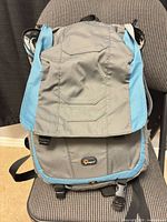 Front view of Lowepro Versapack 200 AW backpack showing gray body, blue trim, front flap, logo