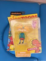 Front view of sealed Arnold figure with pig accessory on Nicktoons card
