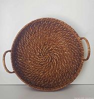 Front view of round woven rattan tray showing handles and weave detail