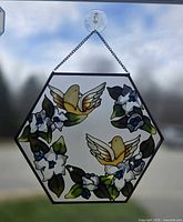 Full view of hexagonal stained glass suncatcher hanging by chain