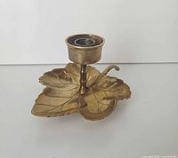 Oblique view of brass leaf candlestick holder showing base, stem, and cup