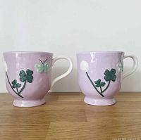 Front view of both lavender mugs showing relief motifs