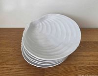 Stack of six white clamshell salad plates