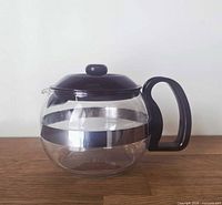 Side view of Pyrex glass carafe showing lid, handle, and stainless band