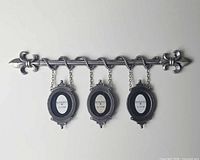 Full view of wall-mounted frame showing rod, fleur-de-lis ends and three hanging oval frames