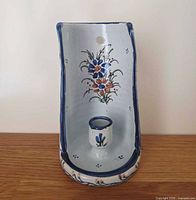 Front view showing floral painting, candle cup, wall hole