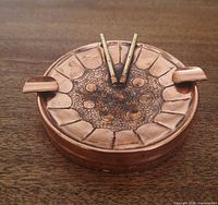 Top view of copper steel-drum ashtray with pan sticks and cigarette rests