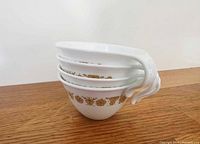 Four stacked Corelle Butterfly Gold cups side view displaying hook handles
