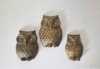 Front view of all three gold tone metal owl plaques