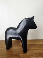 Left profile view of black wooden Dala horse figurine