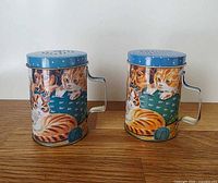 Front view of both shakers showing kittens and puppies artwork and blue lids