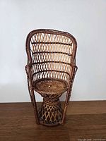 Front view of miniature wicker peacock chair showing high fan back and seat