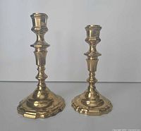Both brass candlesticks front view showing height difference and overall design
