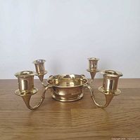 Front view of brass candelabra showing central pillar dish and four taper sockets