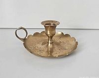 Top angled view of brass chamberstick showing scalloped rim and handle