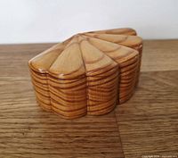 angled side view of carved wooden clamshell box closed