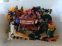 Loose LEGO parts in plastic bin, including dark-red vehicle shell and assorted bricks