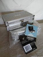 Two silver Vaultz lockboxes, one with retail tags attached, one partially wrapped