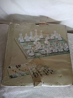 Front of worn cardboard box showing glass chess set image