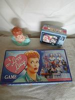 All three I Love Lucy items together: board game box, TV-shaped tin, ceramic bust