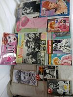 Assorted memorabilia laid out including tin sign, scrapbook, DVDs, photos and calendar