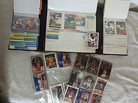 Overview of open binder pages and loose sleeved basketball cards