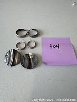 All three earring pairs arranged: medium smooth hoops, small twisted hoops, large disk pair