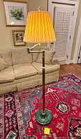 Full view of brass finish floor lamp with green base and orange pleated shade