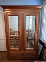 Front view of oak armoire with mirrored doors and drawers