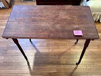 Top view of antique solid wood folding table showing rectangular surface, turned legs, and casters