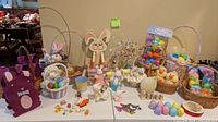 Tabletop display of assorted Easter baskets, plastic eggs, plush animals, ceramic figurines, felt bunny tote and decorative egg tree