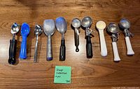 Ten assorted ice cream scoops laid out showing styles, materials and condition