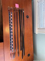 All seven belts laid out showing materials, colors, and buckles