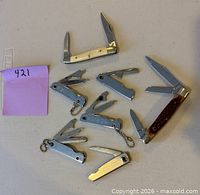 Top view showing all seven assorted pocket knives with some blades open