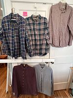 Front view of five long-sleeve flannel shirts on hangers
